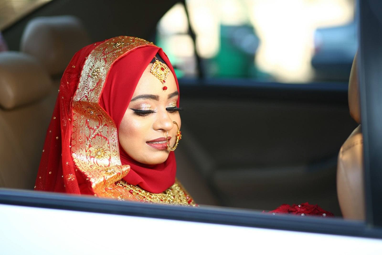 A bride smiling from the wedding car